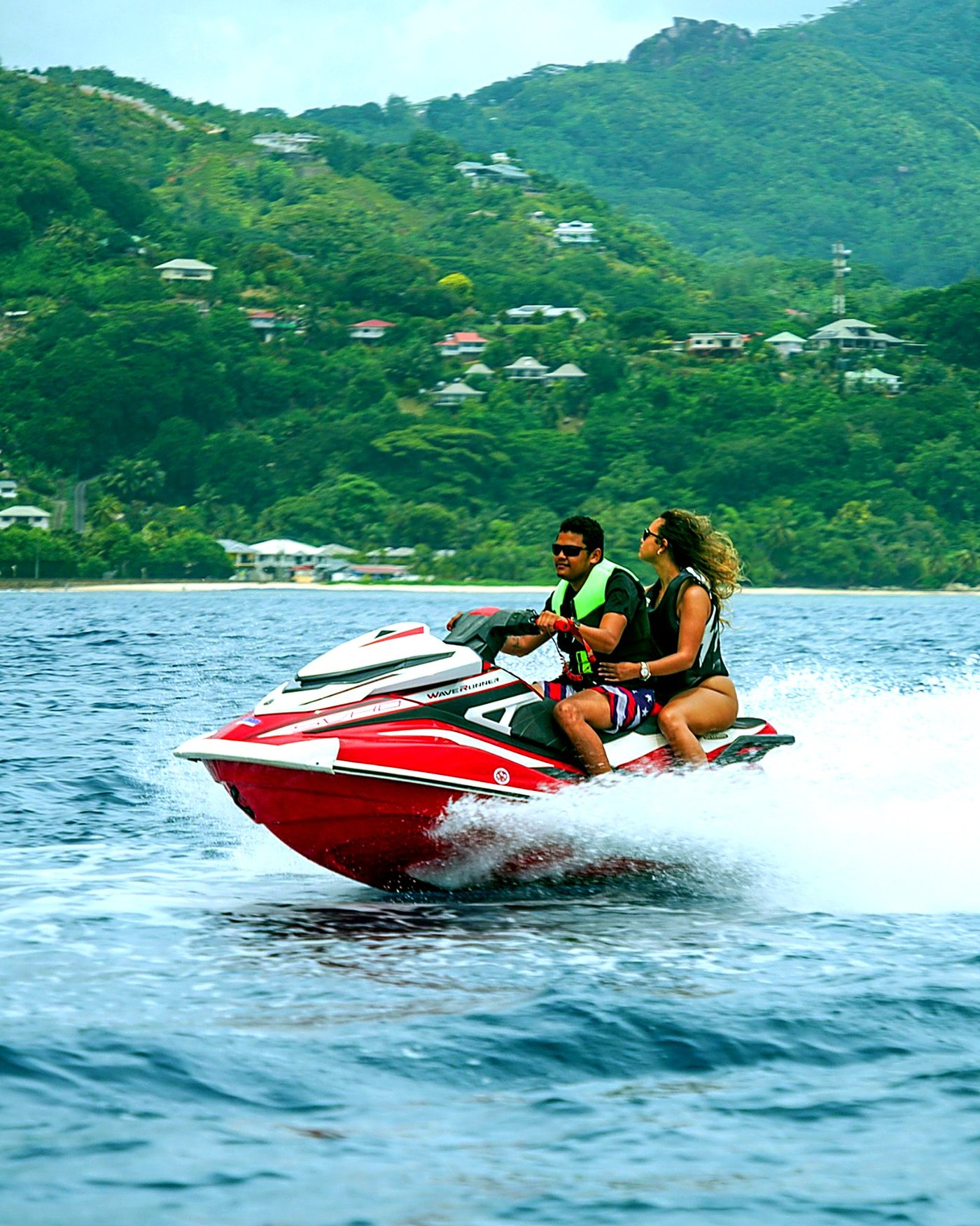 Couple riding a jetski at speed along the Mahé coastline